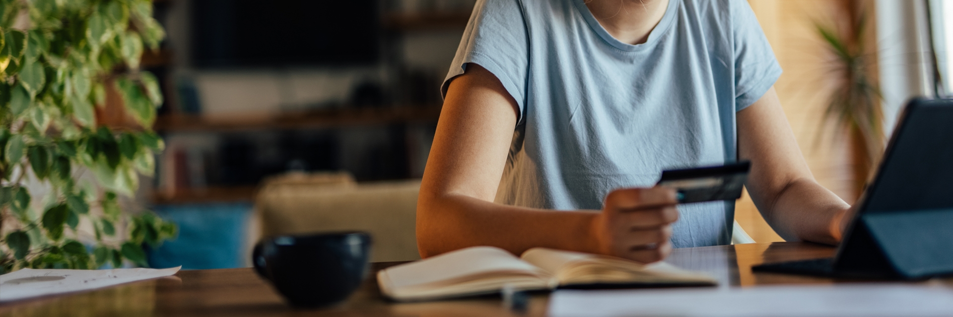 Woman holding a card looking at a tablet